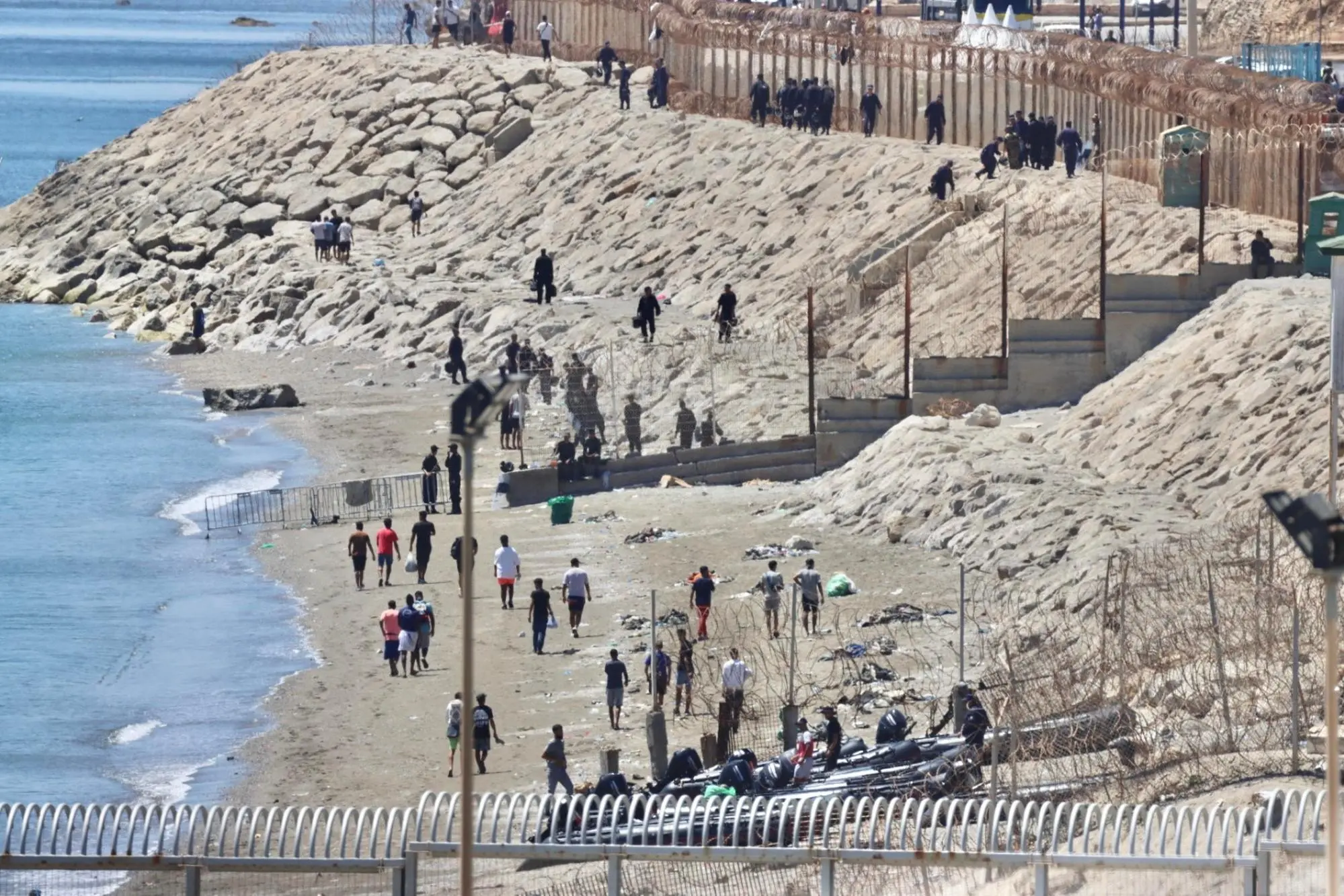 epa13147003 Migrants return across the border fence into Morocco from the Spanish North African enclave of Ceuta, 02 August 2026. The returns follow two days of mass border breaches in which tens of thousands of migrants crossed into Ceuta and attempted entry into nearby Melilla, prompting the deployment of Spanish armed forces and coordinated border returns with Moroccan authorities. EPA/REDUAN