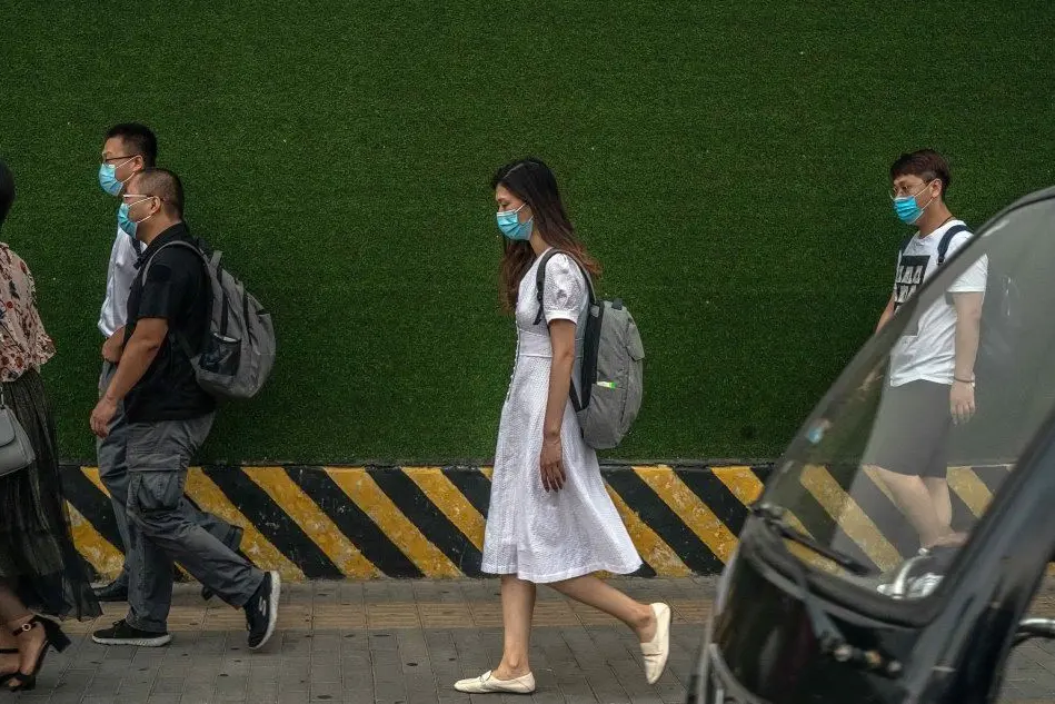 Passanti con le mascherine a Pechino (foto Ansa/Epa)
