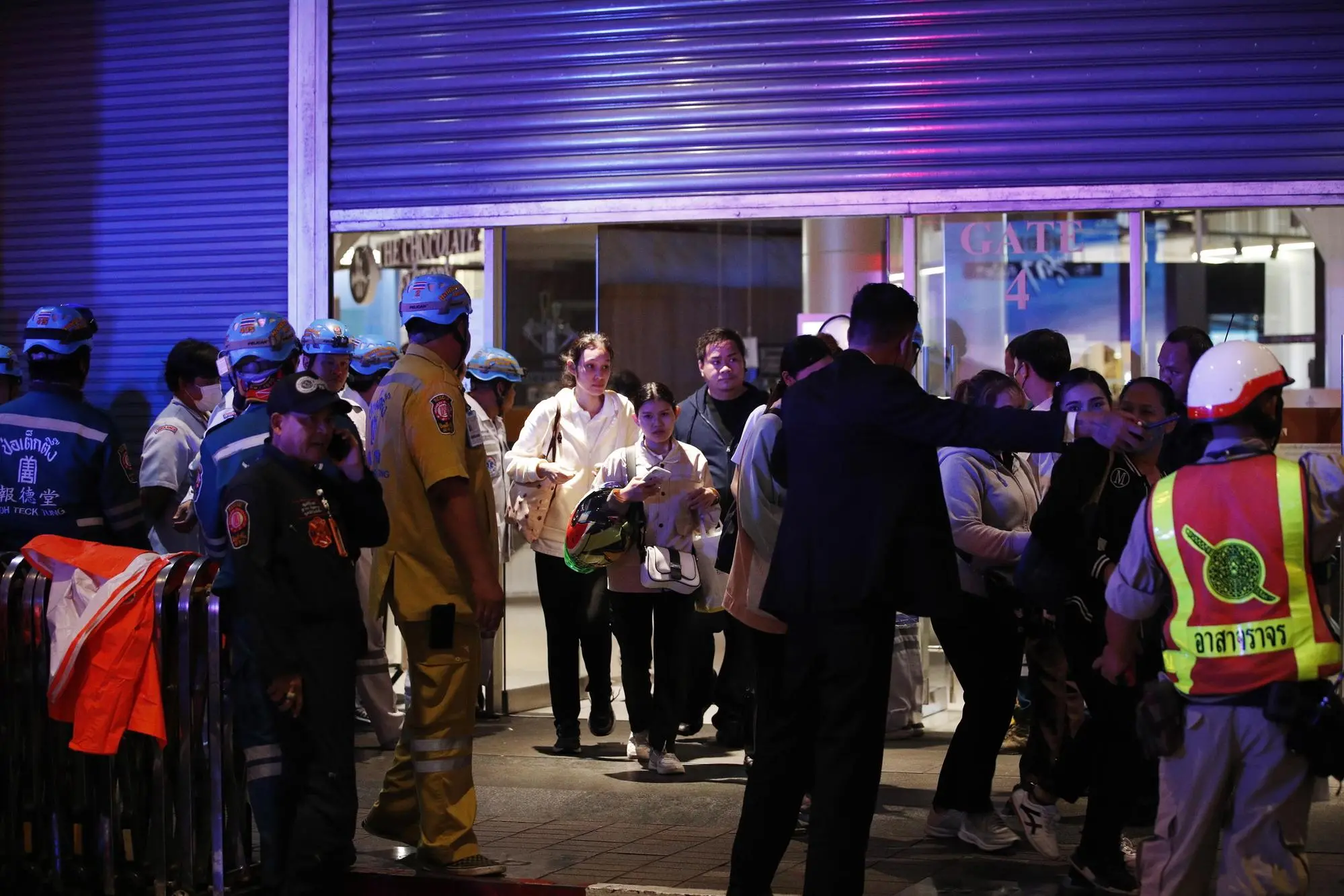 epa10897127 Shoppers are evacuated at an entrance of Siam Paragon Mall following gunshots in Bangkok, Thailand, 03 October 2023. Thai police said the suspected gunman was arrested, while emergency services confirmed at least three people were killed. EPA/RUNGROJ YONGRIT