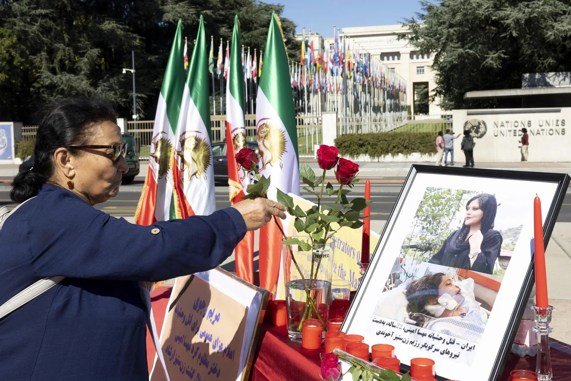epa10195153 A person pays tribute to Amini deposing a rose next to from her portrait after the death of Iranian Mahsa Amini, during a rally on Place des Nations in front of the European headquarters of the United Nations in Geneva, Switzerland, 20 September 2022. Mahsa Amini, a 22 year old Iranian girl, who was arrested by the police unit responsible for enforcing Iran's strict dress code for women, she was detained on 13 September by the Iran's police and was declared dead on 16 September, after she spent 3 days in a coma. EPA/SALVATORE DI NOLFI
