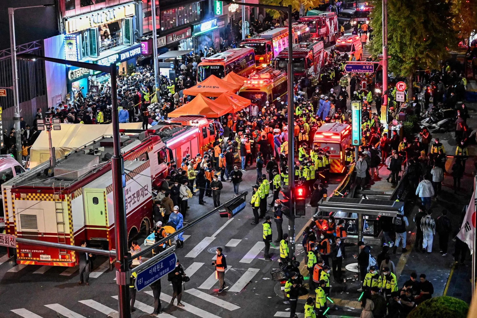 Onlookers, police and paramedics gather where dozens of people suffered cardiac arrest, in the popular nightlife district of Itaewon in Seoul on October 30, 2022. - Dozens of people suffered from cardiac arrest in the South Korean capital Seoul, after thousands of people crowded into narrow streets in the city's Itaewon neighbourhood to celebrate Halloween, local officials said. (Photo by JUNG YEON-JE / AFP)