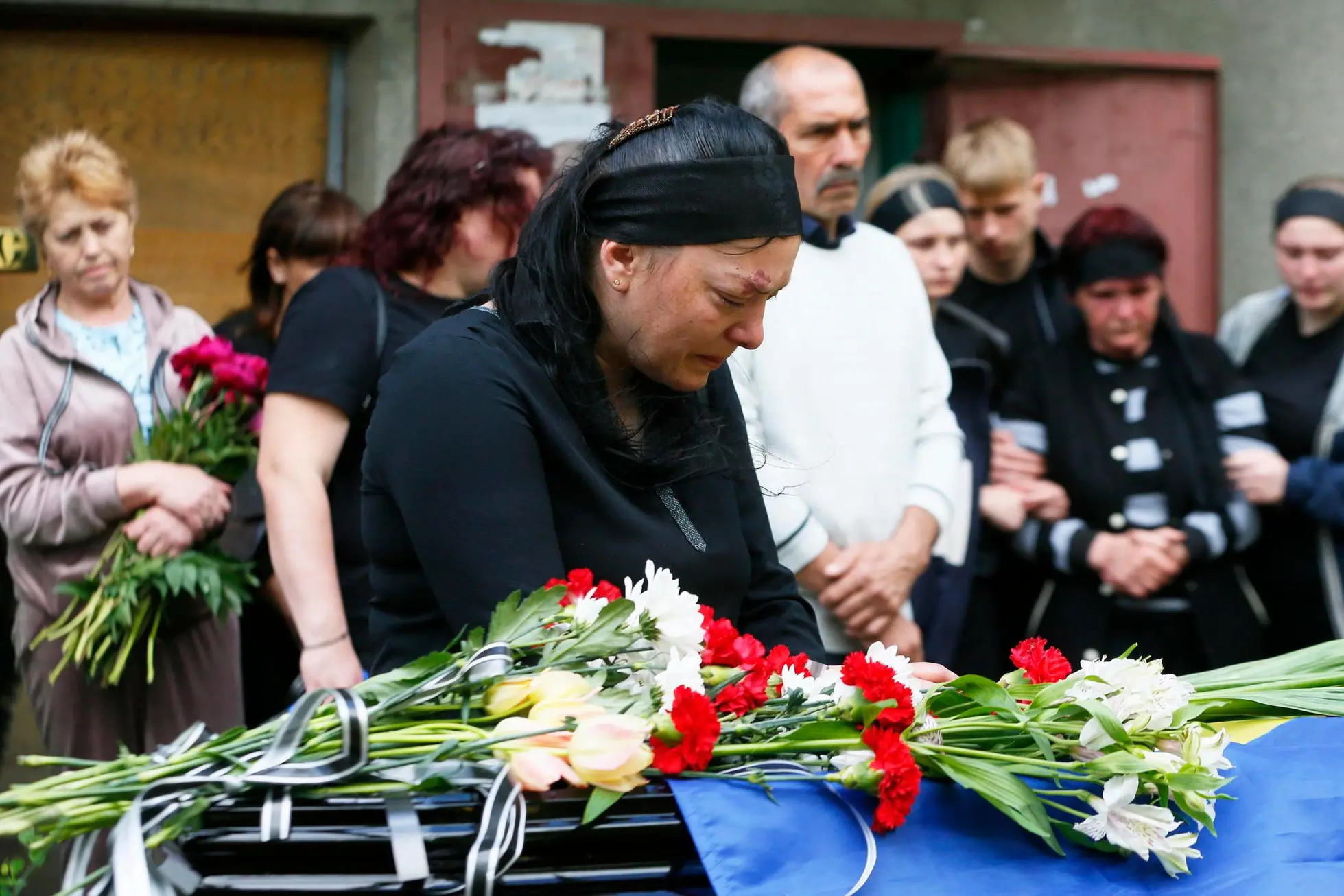 epa09967233 Relatives and friends attend a funeral ceremony of Ukrainian serviceman who was killed in action, in the small city of Rozdilna of Odesa region, Ukraine, 22 May 2022. On 24 February Russian troops entered Ukrainian territory starting a conflict that has provoked destruction and a humanitarian crisis. EPA/STEPAN FRANKO