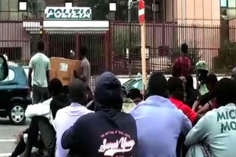 Migranti davanti a un commissariato di polizia