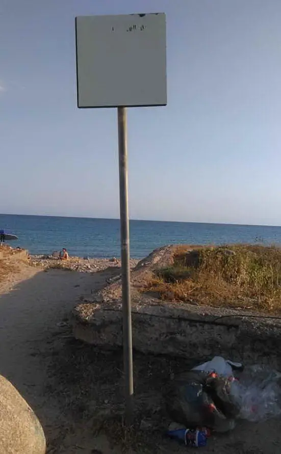 Altri cartelli sbiaditi e rifiuti in prossimità della spiaggia