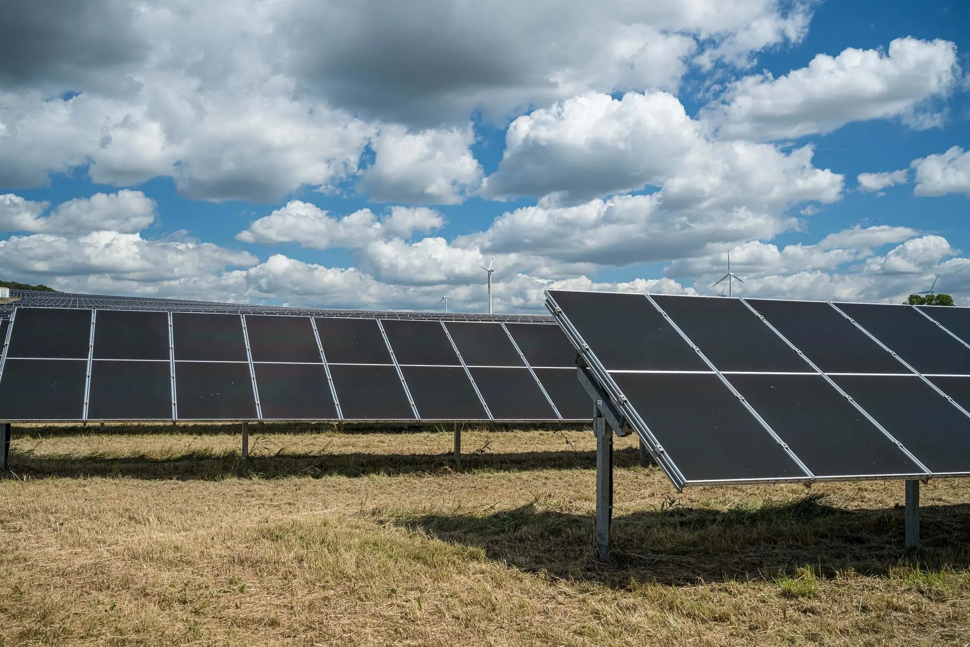 The solar panels in the grain field in the countryside under the cloudy sky