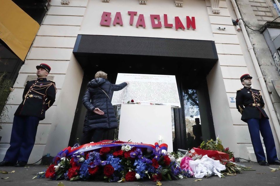Una donna tocca la targa commemorativa all'ingresso del Bataclan (Ansa)