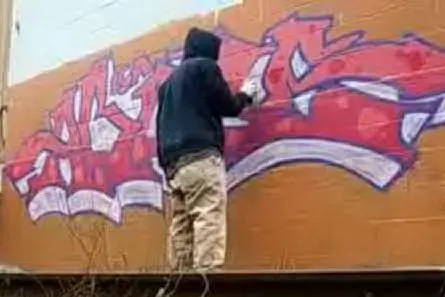 Un giovane impegnato in un graffito sul muro - foto simbolo