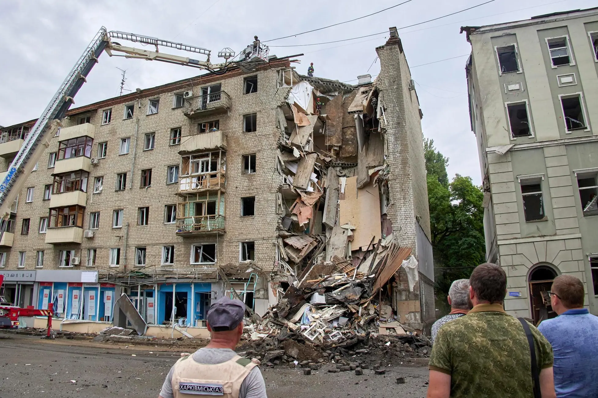 epa10065459 Locals look on a damaged residential building following a Russian rocket strike hitting the city of Kharkiv, Ukraine, 11 July 2022. At least six people were killed and 31 injured in the Kharkiv area on 11 July, the head of the Kharkiv regional administration Sinegubov said. Kharkiv and surrounding areas have seen increased shelling and airstrikes from Russian forces. Russian troops on 24 February entered Ukrainian territory, starting a conflict that has provoked destruction and a humanitarian crisis. EPA/SERGEY KOZLOV