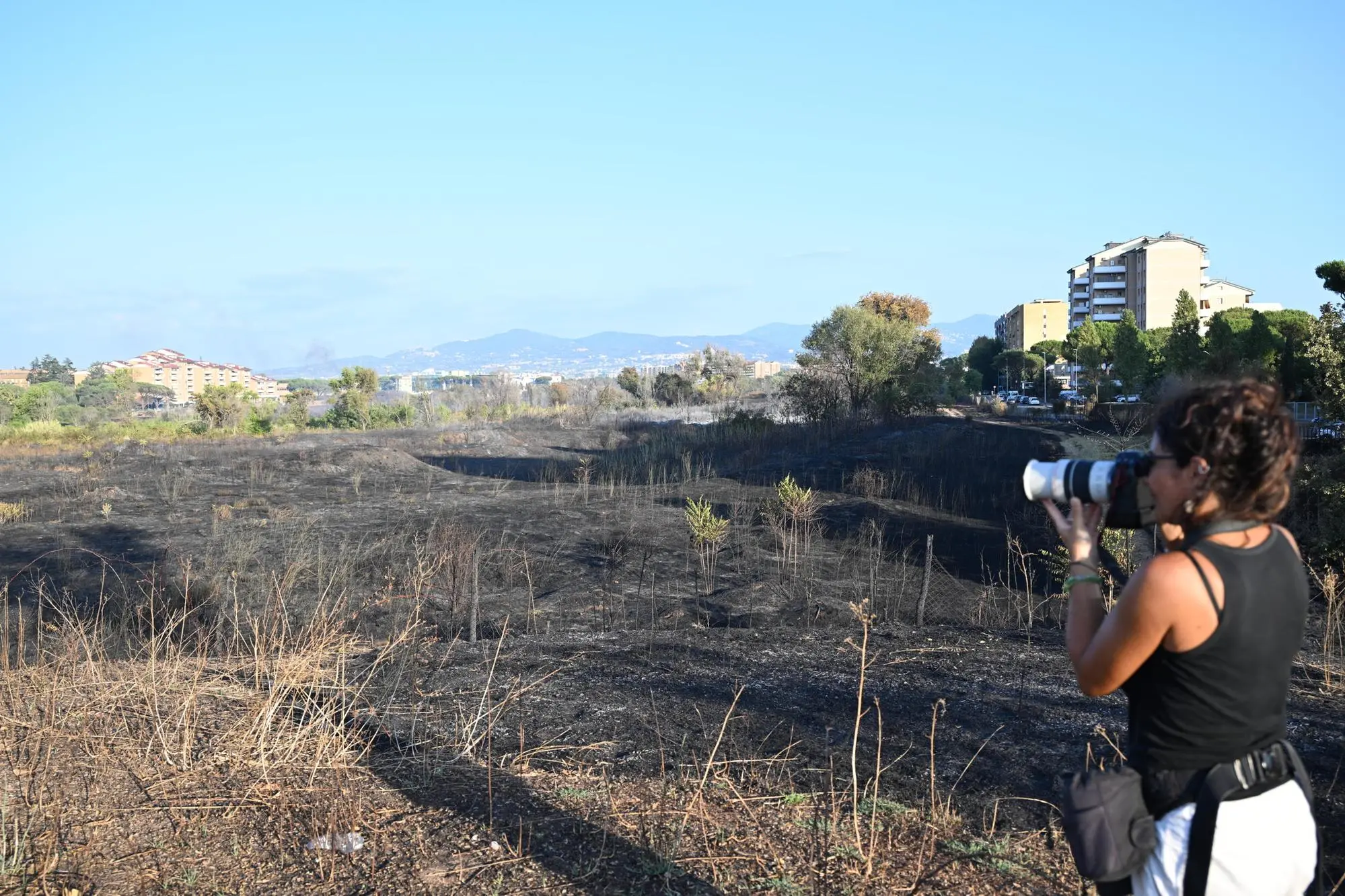 Il pratone di Torre Spaccata dove hanno preso fuoco delle sterpaglie, Roma, 21 agosto 2024. Secondo quanto si apprende un Vigile del Fuoco e tre operatori della protezione civile sono stati portati in ospedale in codice rosso per le ustioni riportate durante l'ntervento. ANSA / CLAUDIO PERI