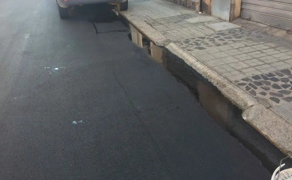 La strada asfaltata con l'acqua che scorre dalla falla