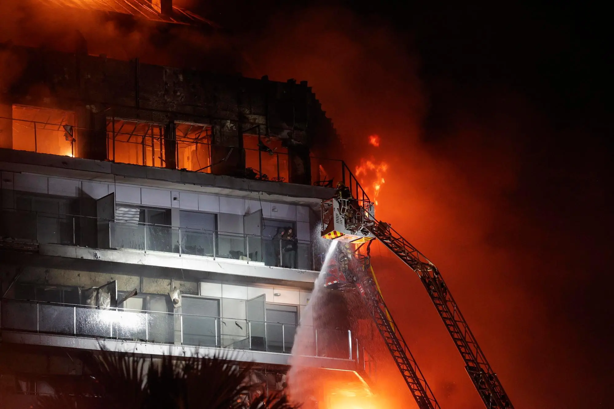 epaselect epa11173266 Firemen try to extinguish a fire of a 14-story residential building in Valencia, eastern Spain, 22 February 2024. At least seven people were injured during the ongoing fire, and two people trapped on a balcony were rescued by firefighters. EPA/MANUEL BRUQUE