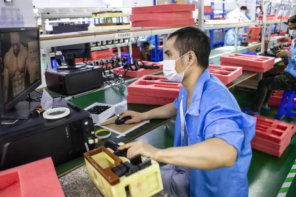 Operai al lavoro con la mascherina a Shenzen (Ansa)