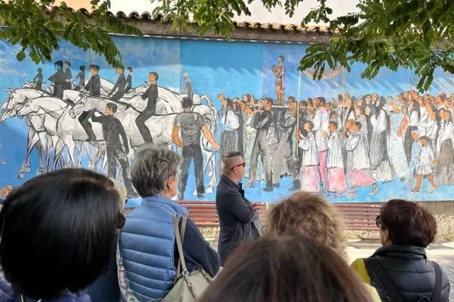 Visitatori a Oliena ammirano il grande dipinto "La processione" di Liliana Cano