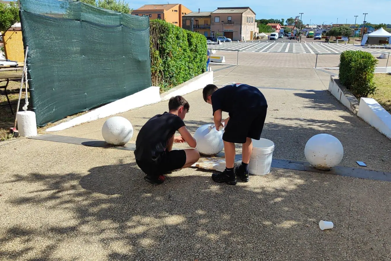 Alcuni ragazzi impegnati nella pulizia dell'area verde di piazza Stagno