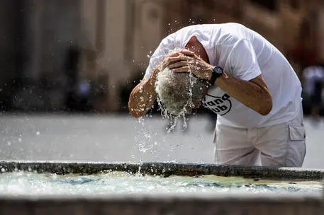 Una persona si rinfresca dal caldo a una fontana (Ansa)
