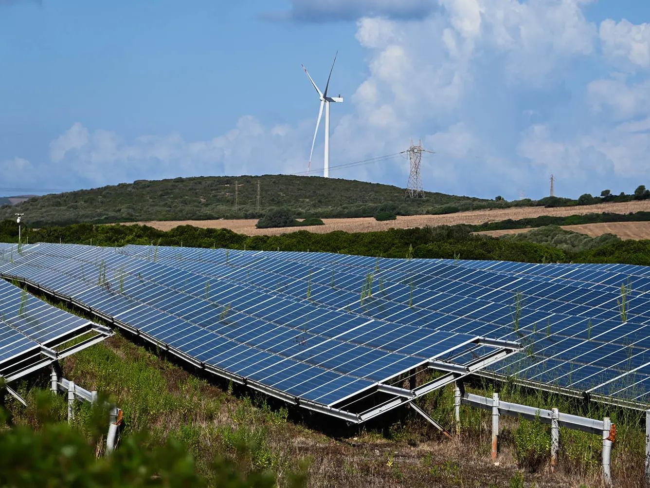 Un campo fotovoltaico e sullo sfonfo pale eoliche (Archivio)