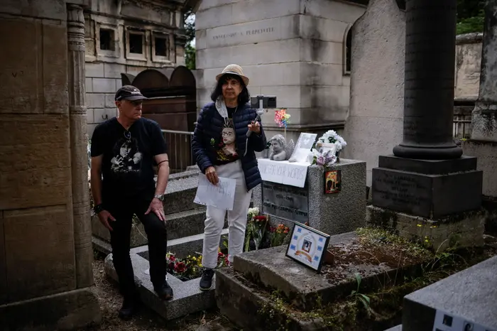Fan davanti alla tomba di Jim Morrison nel cimitero parigino di Père-Lachaise (Ansa-Epa)