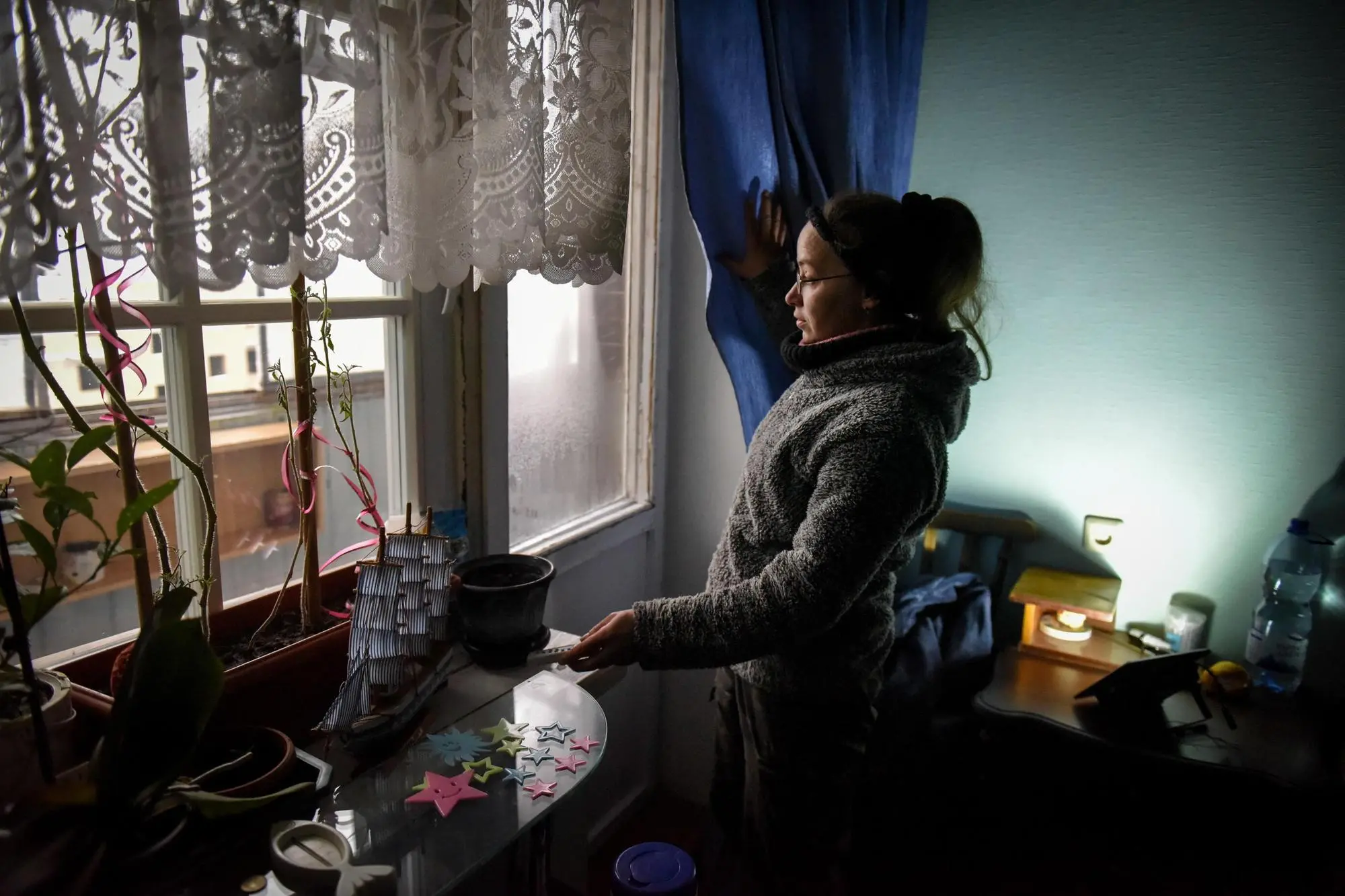 epaselect epa10347135 Tetiana demonstrates the functioning of a lamp (R, back) charging from a solar panel, inside her flat at a damaged apartment block in Horenka, near Kyiv, Ukraine, 03 December 2022. Tetiana and her husband, Ihor, returned to their flat in April after the apartment block was damaged by Russian shelling during combat in the Kyiv region last March. The building was partially destroyed in the attack, but their flat, currently without water and electricity supply, survived. In November 2022, street artist Banksy painted a series of artworks in Ukraine, including at this damaged building in Horenka. Russian troops on 24 February entered Ukrainian territory, starting a conflict that provoked destruction and a humanitarian crisis. EPA/OLEG PETRASYUK
