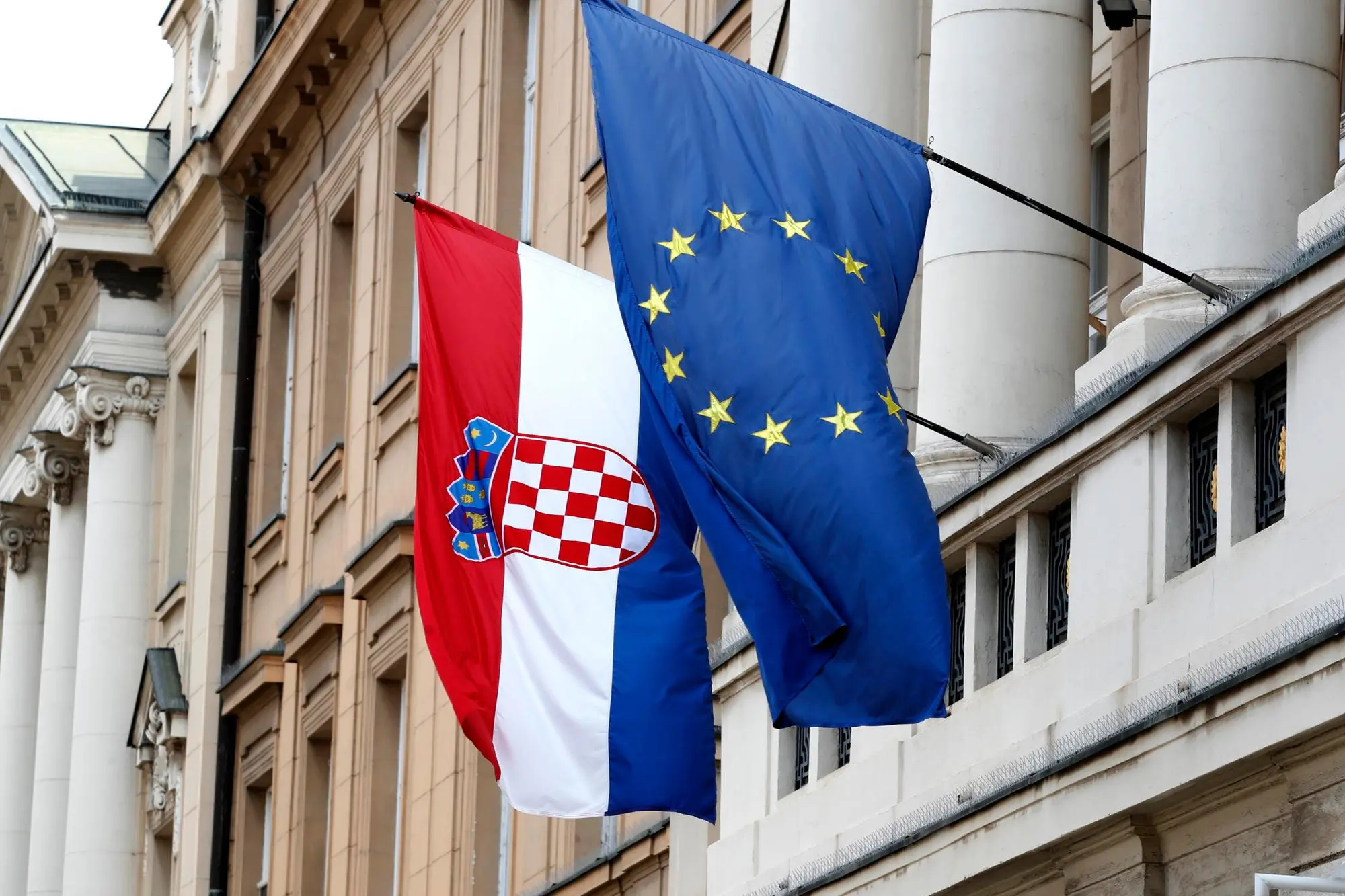 epa09960504 The flags of Croatia (L) and European Union (EU) hang from the facade of the Parliament building at old town in Zagreb, Croatia, 20 May 2022. Croatia, which joined the EU in 2013, is set to join the Eurozone in January 2023, with the introduction of the euro as the country's official currency after Croatian lawmakers voted in favor of legislation to bring the shared currency. EPA/ANTONIO BAT