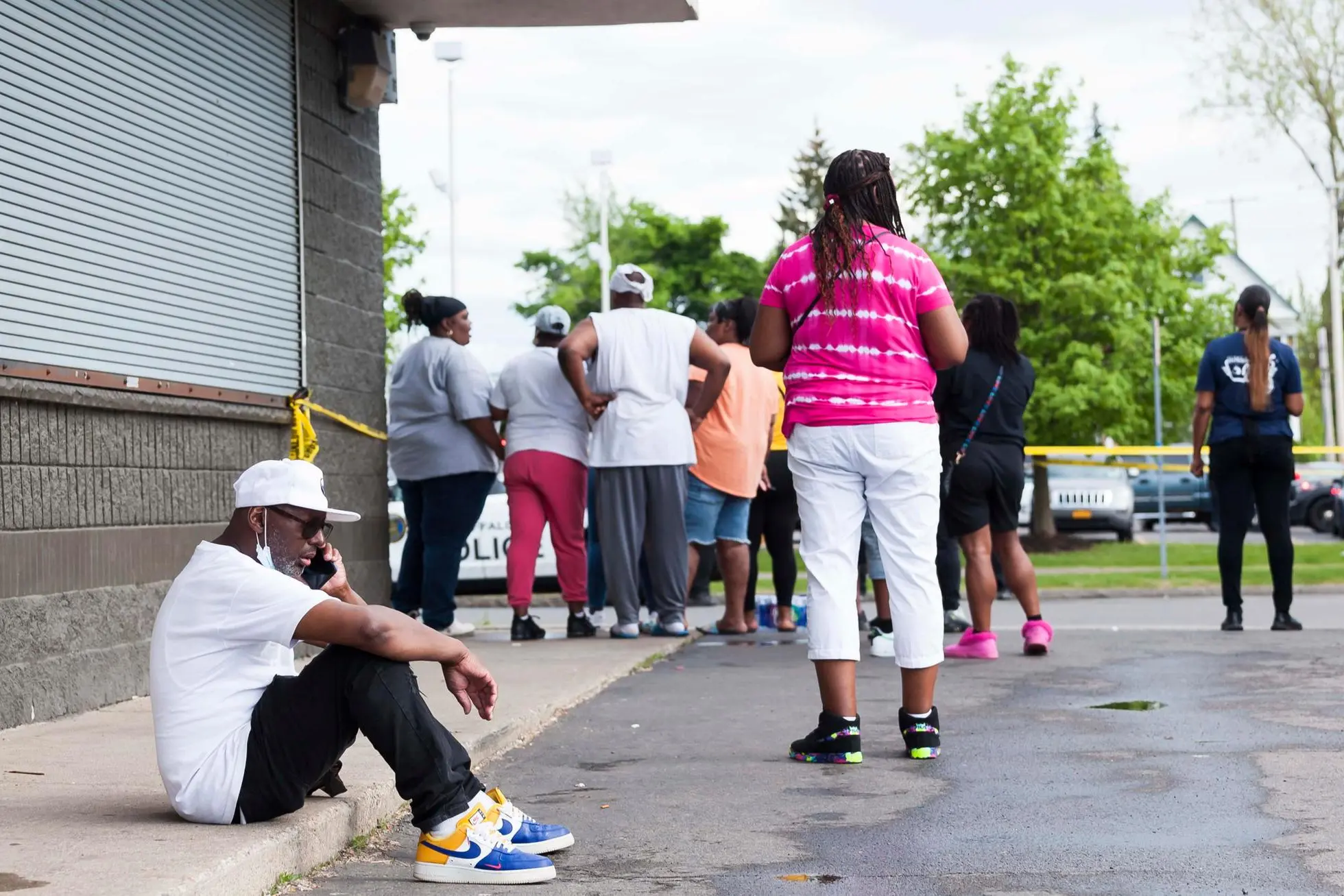 epa09947832 Community members gather near the scene of a mass shooting at the Tops Friendly Market grocery store in Buffalo, New York, USA, 14 May 2022. A gunman, who has been taken into custody by police, reportedly opened fire at the market killing as many as 10 people. EPA/BRANDON WATSON