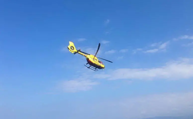 L'elicottero mentre trasporta il ferito (foto Mariangela Pala)