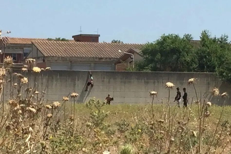 I migranti mentre scavalcano il muro (Foto L'Unione Sarda - Manunza)