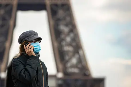 epa09038484 A woman wearing a surgical face mask walks near the Eiffel Tower in Paris, France, 26 February 2021. Paris City Hall suggests a third lockdown, for three weeks, to curb the rate of Covid-19 coronavirus infections. EPA/IAN LANGSDON