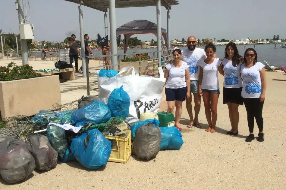 L'assessore comunale Claudia Medda (seconda da destra), alcuni volontari e una parte dei rifiuti recuperati in mare