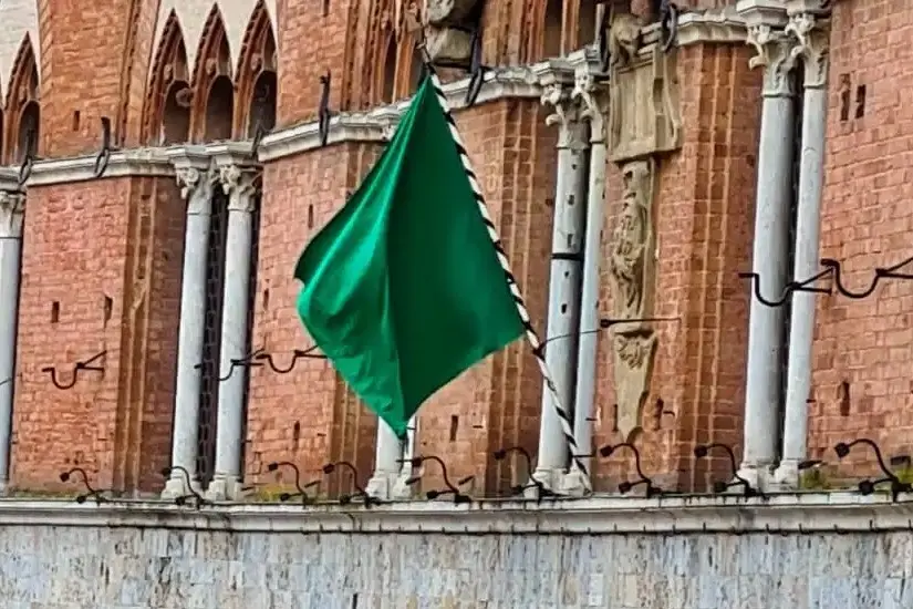 La bandiera verde esposta dalle trifore del Palazzo Pubblico, il Municipio, comunica il rinvio della corsa