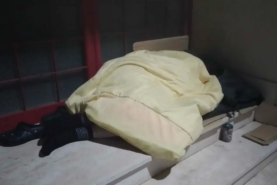 Il clochard addormentato sotto un portone ieri notte ad Alghero (foto Tellini)