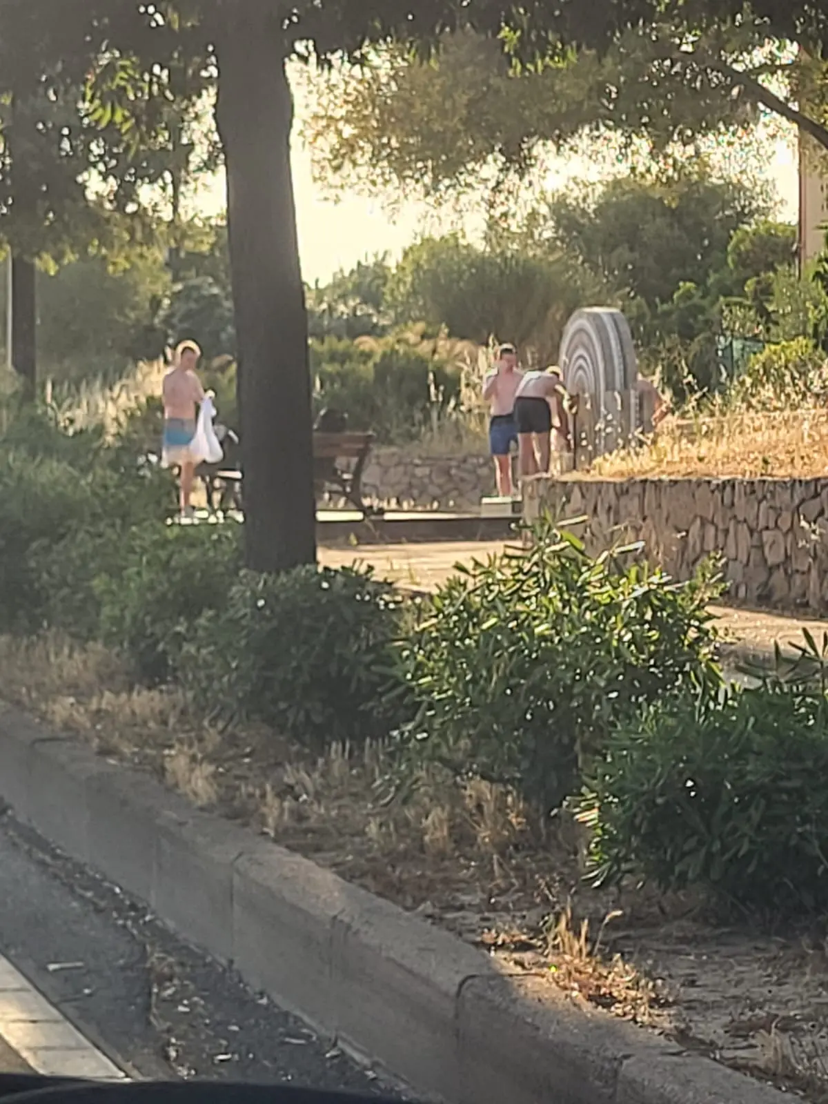 I turisti che fanno la doccia nella fontana a Olbia