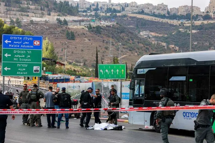 EDITORS NOTE: Graphic content / Israeli security forces gather by a body next to a bus at the Ramot road junction in Israeli-annexed east Jerusalem on September 8, 2025. Israel's emergency service said it received reports of more than a dozen people injured by gunfire on September 8, with police saying the assailants had been "neutralised". Israel's Magen David Adom agency said paramedics and ambulance crews were providing medical treatment and evacuating five "seriously wounded people" who had been sent to hospitals in Jerusalem. (Photo by Menahem Kahana / AFP)