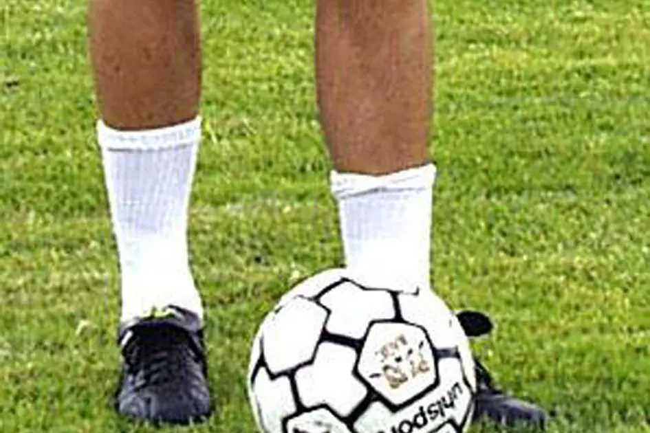 un pallone da calcio tra le gambe di un giocatore-