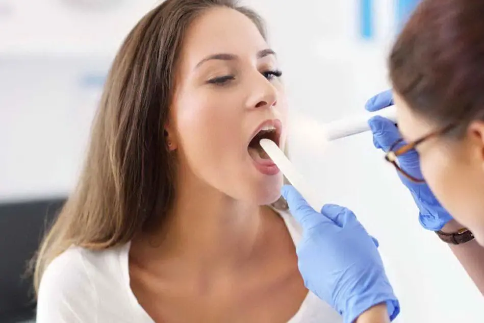 Una otorinolaringoiatra controlla le tonsille di una paziente
