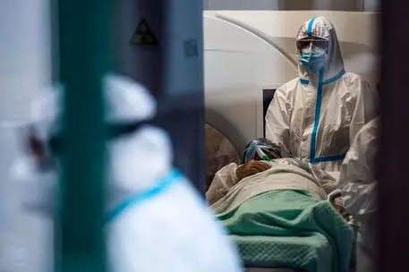 A patient is accompanied to carry out medical examinations for Covid-19 by health workers wearing protective suits and masks through a protected path of the Covid Emergency Department of the Umberto I Hospital called "Fever Path" dedicated exclusively to COVID patients, during the Coronavirus Covid-19 pandemic emergency in Rome, Italy, 02 December 2020. ANSA/ANGELO CARCONI