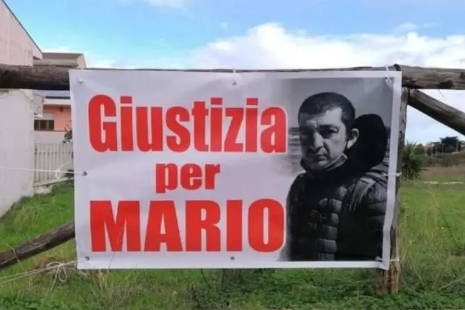 Lo striscione "Giustizia per Mario" nel luogo del delitto (foto Pala)