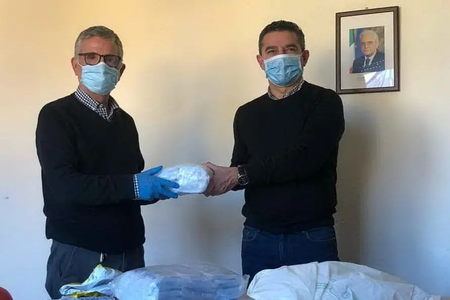 Osvalfo Pisu, a sinistra, consegna le mascherine al sindaco Puddu (L'Unione Sarda - foto Serreli)