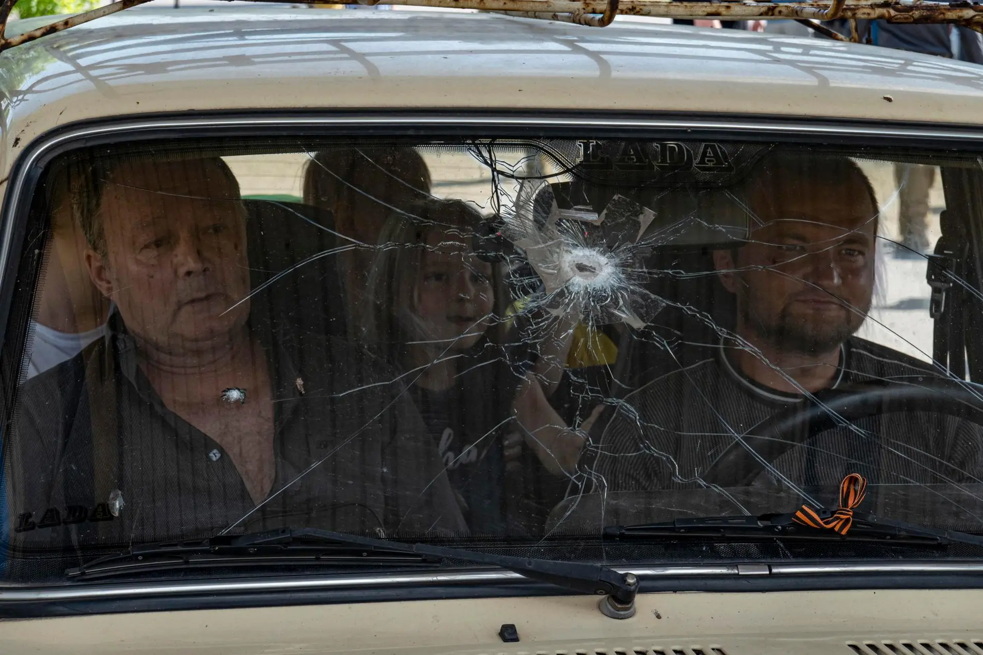 epa10010059 A picture taken during a visit to Mariupol organized by the Russian military shows a local family drives on a car with a broken windshield in Mariupol, Ukraine, 12 June 2022. Russian Defense Minister Sergei Shoigu said 'In Mariupol, water and electricity supply to residential areas is gradually being restored, streets are being cleared, the first social facilities have begun to function.' On 24 February Russian troops entered Ukrainian territory starting a conflict that has provoked destruction and a humanitarian crisis. According to the UNHCR, more than six million refugees have fled Ukraine, and a further 7.7 million people have been displaced internally within Ukraine since. EPA/SERGEI ILNITSKY