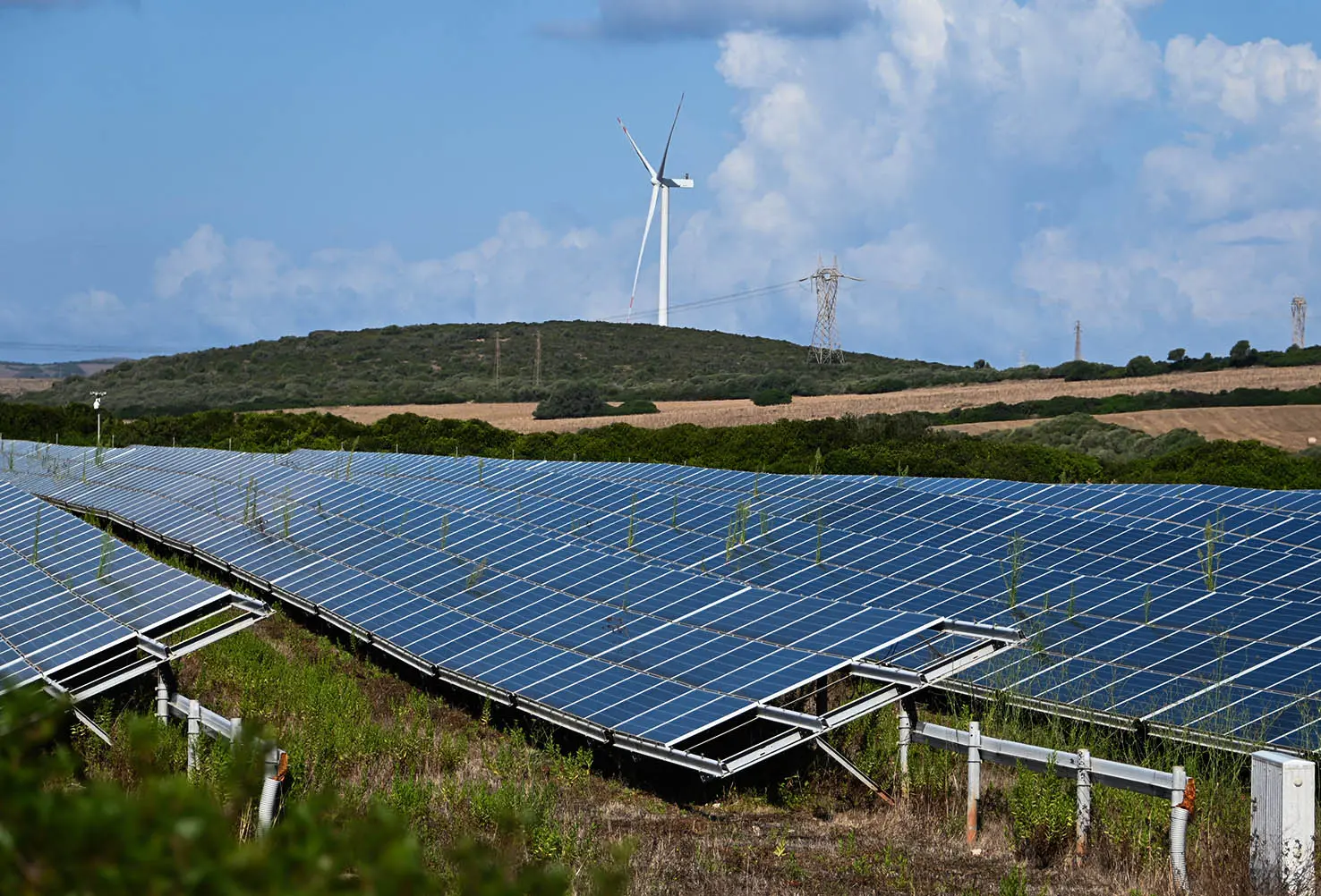 Un campo fotovoltaico e sullo sfonfo pale eoliche