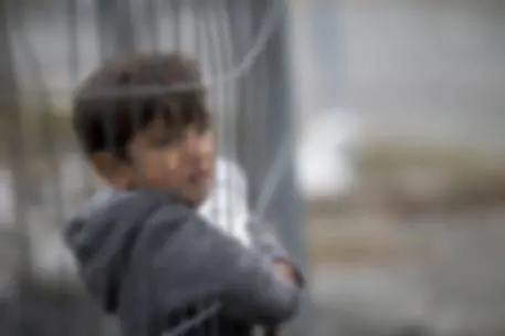 epaselect epa04998473 A migrant child looks through a fence at the Slovenian-Austrian border in Spielfeld, Austria, 27 October 2015. Europe is contending with its largest population movement since World War II, with almost 700,000 migrants and asylum seekers arriving by sea this year - many of them from war-torn Syria. Tens of thousands have been crossing the western Balkans to make their way from Turkey to wealthy northern European countries such as Germany and Sweden. The nations along the migratory route have largely passed on people with little coordination, leading to recriminations and tensions between neighbours. EPA/ERWIN SCHERIAU