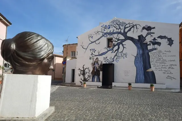 Il murale all'ingresso del museo MacLula e la scultura dedicata a Grazia Deledda