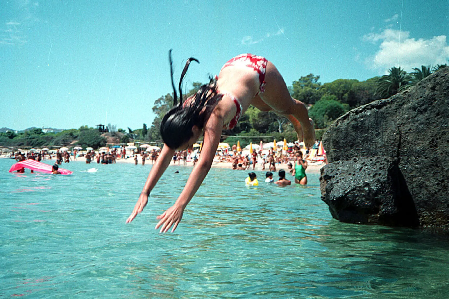 Una ragazza si tuffa nel mare davanti alla spiaggia di Santa Margherita di Pula