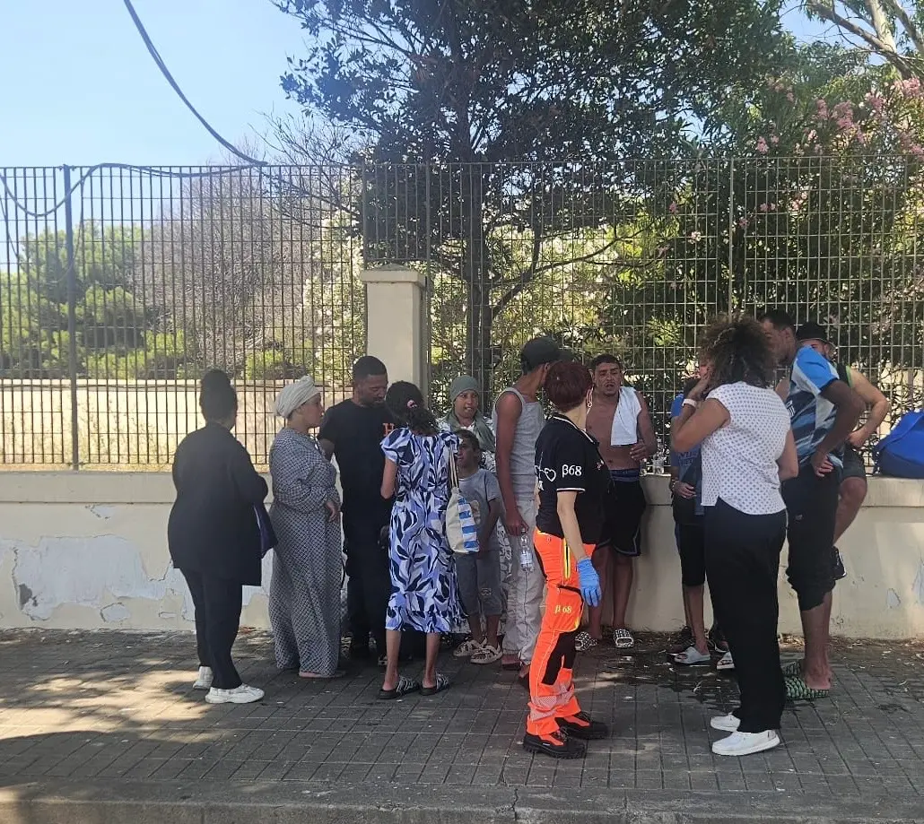 I migranti in sosta all’ombra in attesa del trasferimento (Foto: Fabio Murru)
