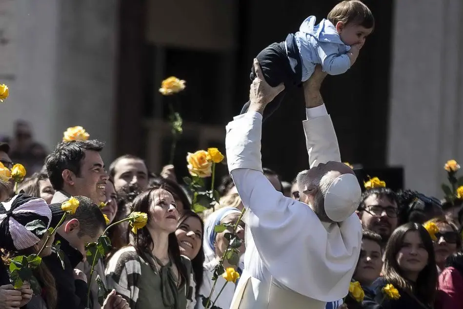 John Malkovich nei panni del Papa mentre solleva un bimbo in piazza San Pietro