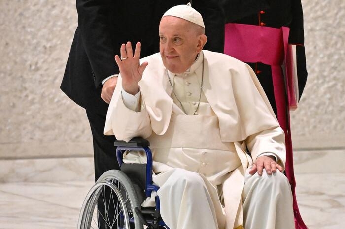 Pope Francis waves as he arrives on wheelchair during the audience to the Participants to Plenary Assembly of the International Union of Superiors General in the Paul VI hall at the Vatican, on May 5, 2022 . (Photo by Alberto PIZZOLI / AFP)