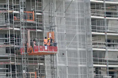 Operai edili al lavoro sulla facciata di un palazzo ricoperto da ponteggi, Milano, 14 giugno 2022. ANSA/DANIEL DAL ZENNARO