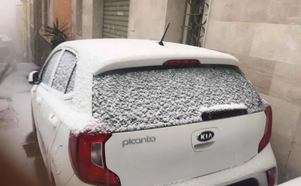 I fiocchi di neve si accumulano sulle auto