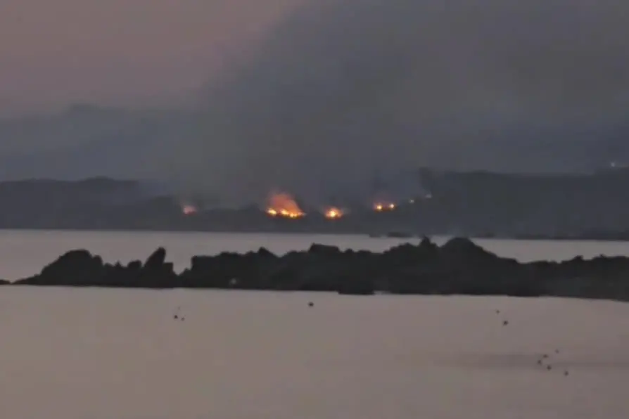 L'incendio di Monti Russu ripreso questa mattina all'alba dal borgo turistico di Vignola (foto Busia)
