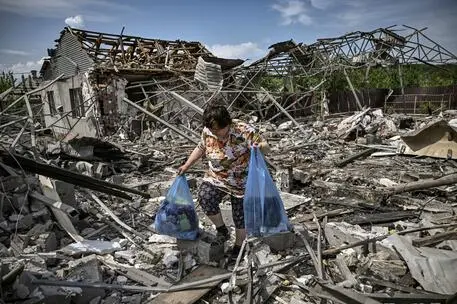 TOPSHOT - A woman collects belongings in the ruble of their house after a strike destoyed three houses in the city of Slovyansk in the eastern Ukrainian region of Donbas on June 1, 2022. (Photo by ARIS MESSINIS / AFP)