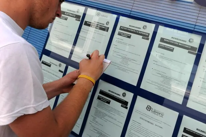 Un ragazzo davanti a un'agenzia interinale (Franco Silvi, Ansa)